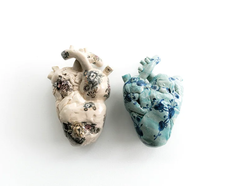 Pièces de céramique artisanales en cours de séchage sur des étagères en bois, avec des outils de modelage à proximité.