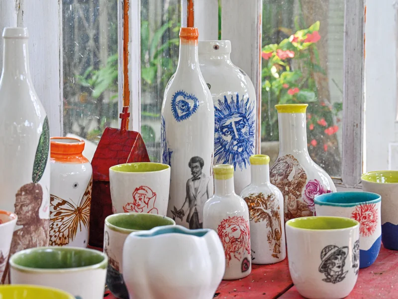 Installation artistique de fusils en céramique, l'un blanc et l'autre sombre, exposés dans un musée historique.