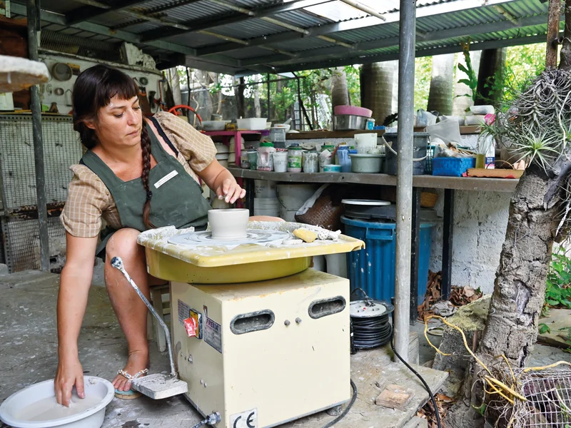 Mains d'Alice Aucuit collectant des cendres végétales ou de l'argile sur une plage volcanique de La Réunion.