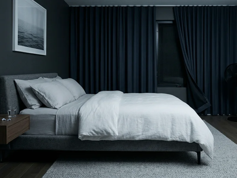 Chambre à coucher fraîche et sombre, avec un thermomètre affichant 18°C, favorisant un sommeil profond.